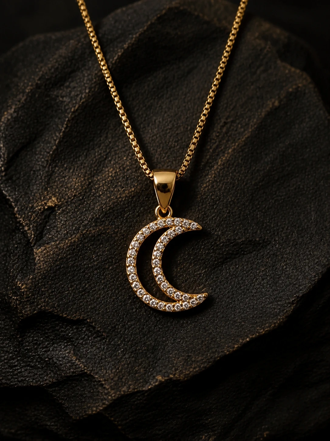 Colgante de luna dorado con piedras sobre fondo negro